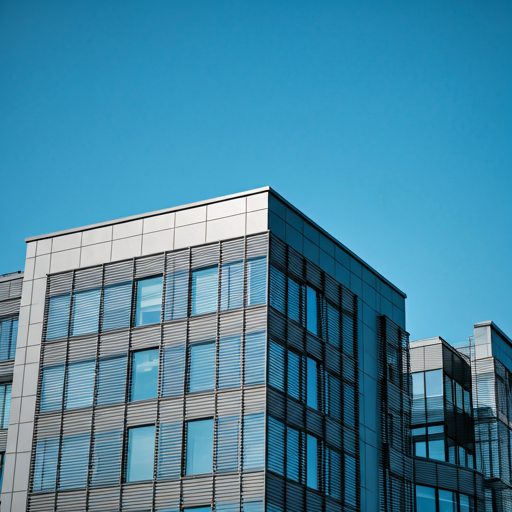 Modernes Bürogebäude mit Glasfassade vor blauem Himmel